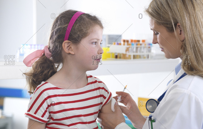 Female doctor giving a young girl a routine vaccination in the clinic