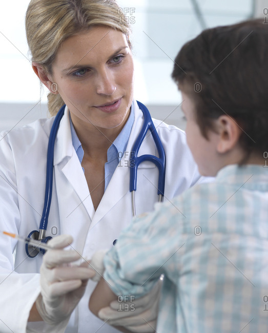 Female doctor giving a young boy a vaccination in the clinic