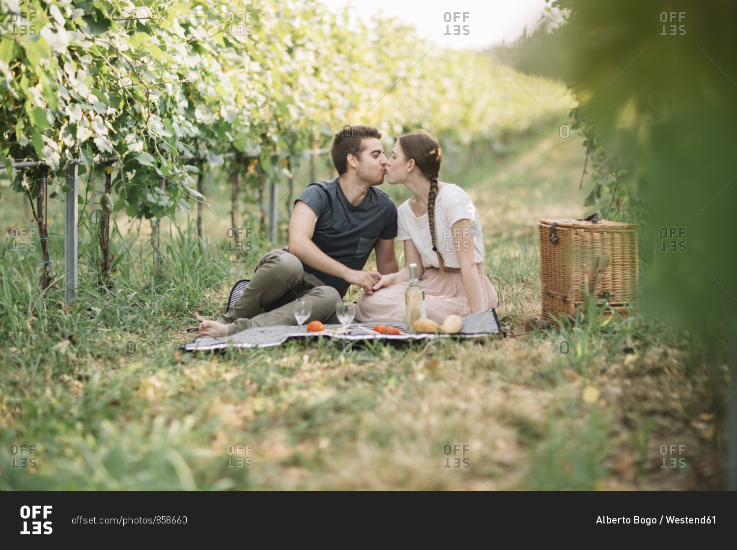 Kissing young couple having picnic in the vineyards