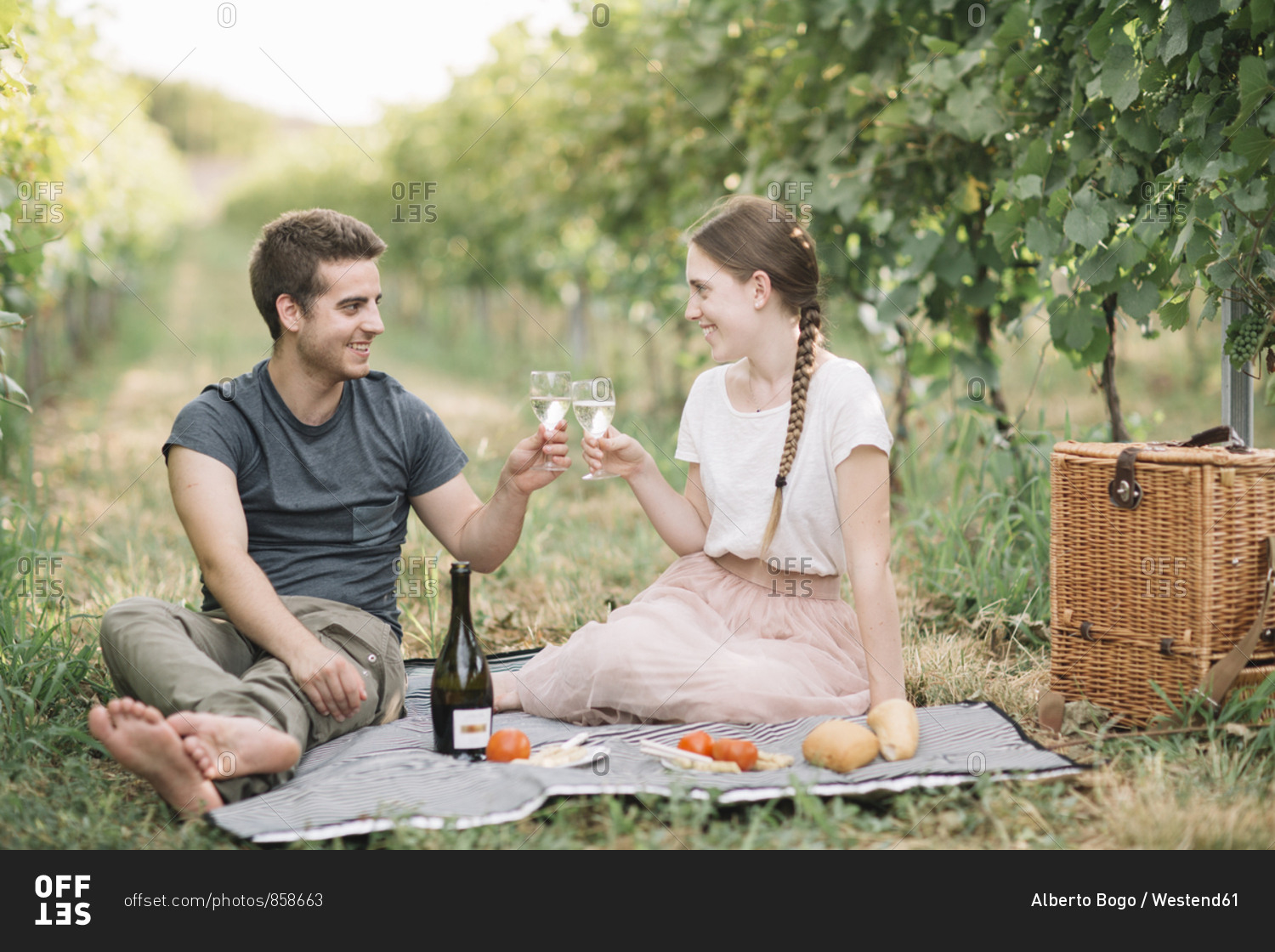 Happy young couple having picnic in the vineyards- toasting with Prosecco