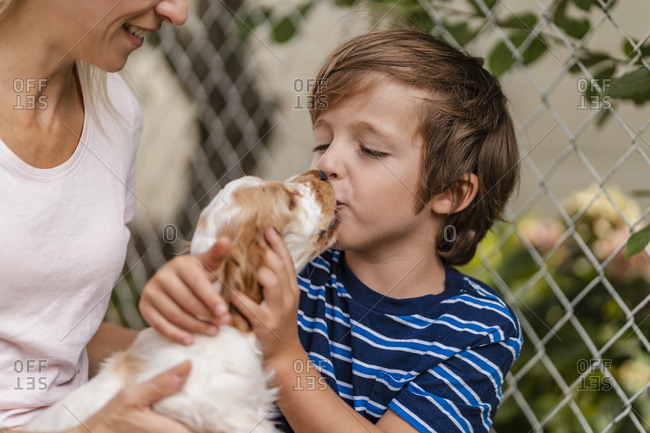 Mother and son cuddling with cute dog puppy
