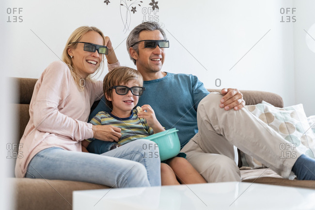 Father- mother and son wearing 3d glasses on couch at home watching Tv