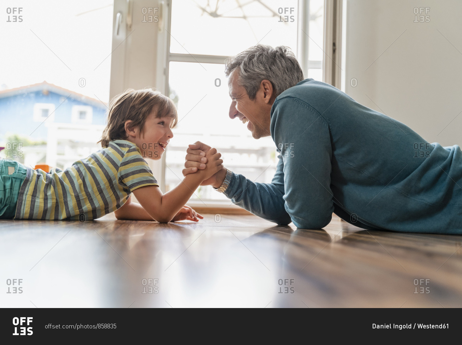 Father and son lying on the floor at home arm wrestling