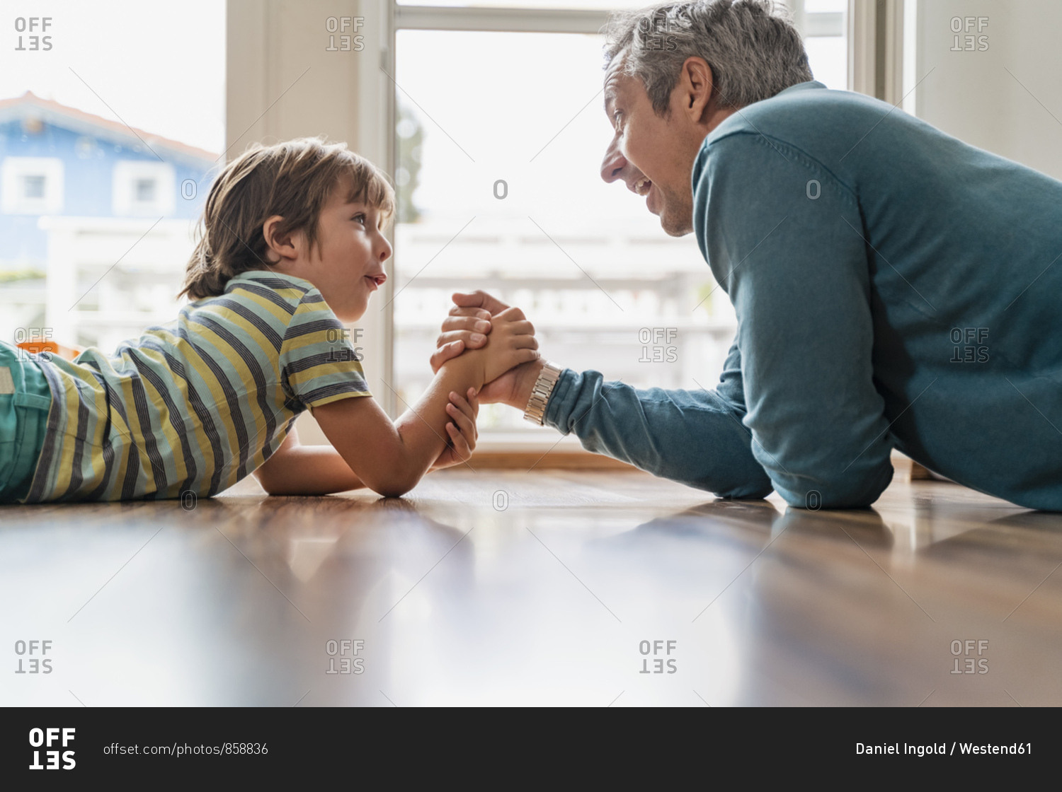 Father and son lying on the floor at home arm wrestling