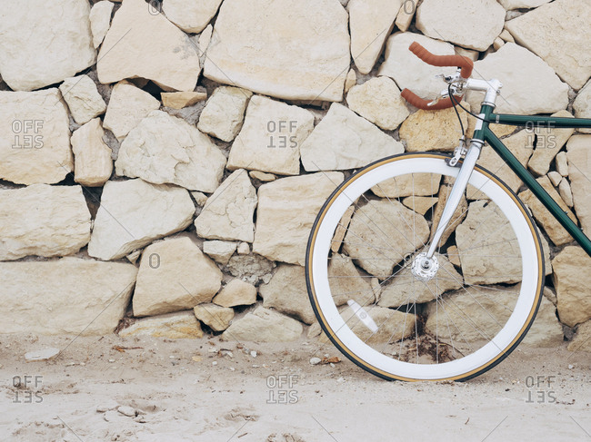 Fixie bike leaning against natural stone wall- partial view