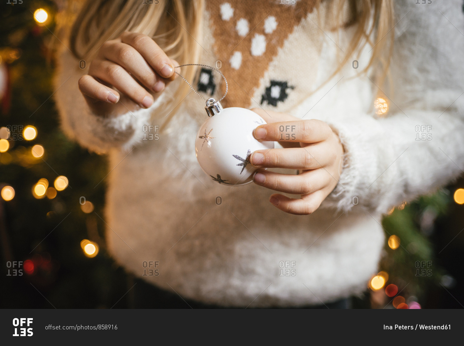Decorating the christmas tree- girl holding a white bauble with silver stars