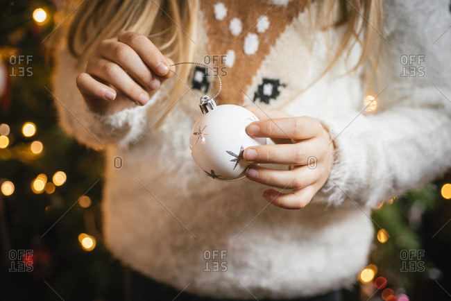 Decorating the christmas tree- girl holding a white bauble with silver stars
