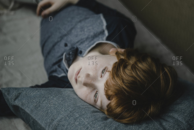 Portrait of daydreaming boy lying on couch looking at distance
