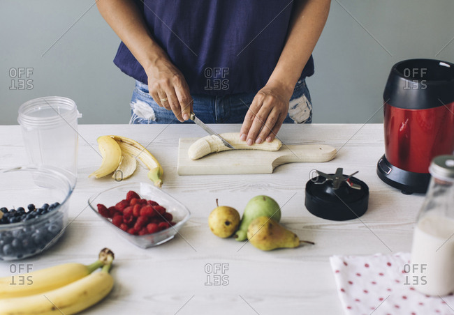 Woman cutting banana for a smoothie