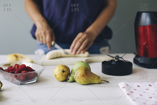 Woman cutting banana for a smoothie