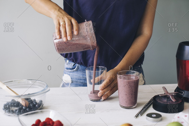 Woman pouring smoothie into glasses