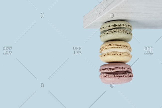 A pile of delicious macarons of hanging upside down from a white wooden board