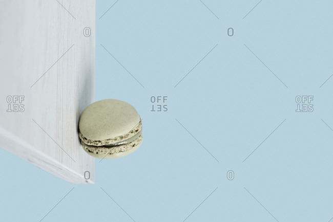 A delicious green macaron stuck on a vertical white wooden board