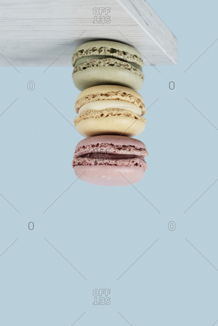 A pile of delicious macarons of hanging upside down from a white wooden board