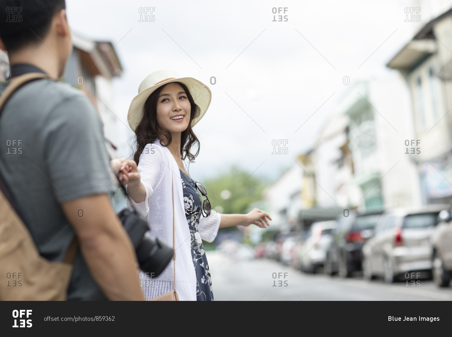 Happy young Chinese couple holding hands on street