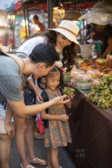 Happy young Chinese family eating snack in market