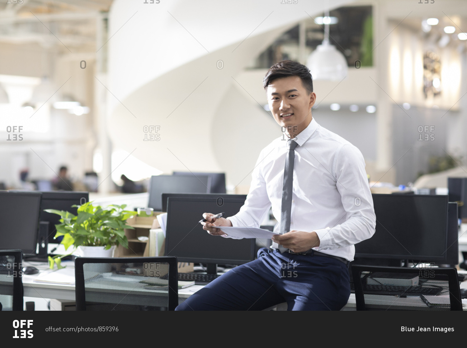 Young Chinese businessman holding file in office