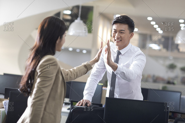 Chinese business people giving high five in office