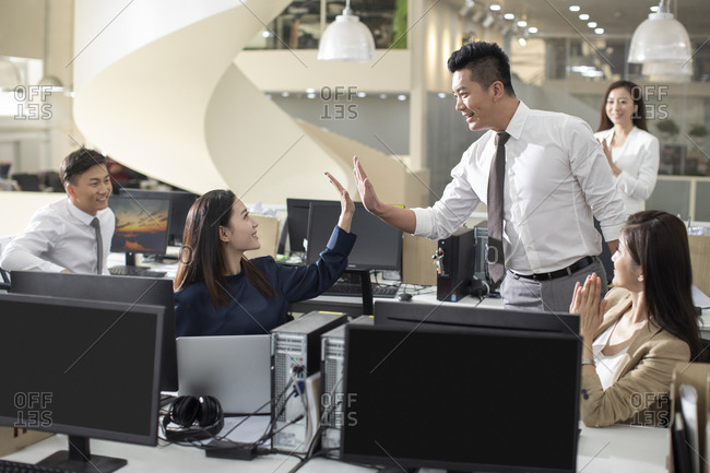 Chinese business people giving high five in office
