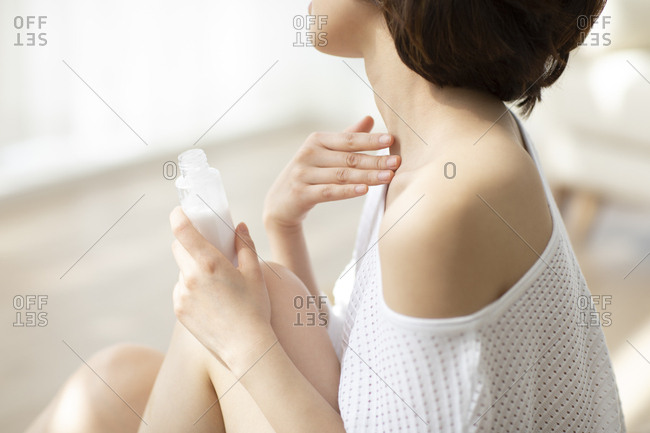 Young Chinese woman applying moisturizer at home