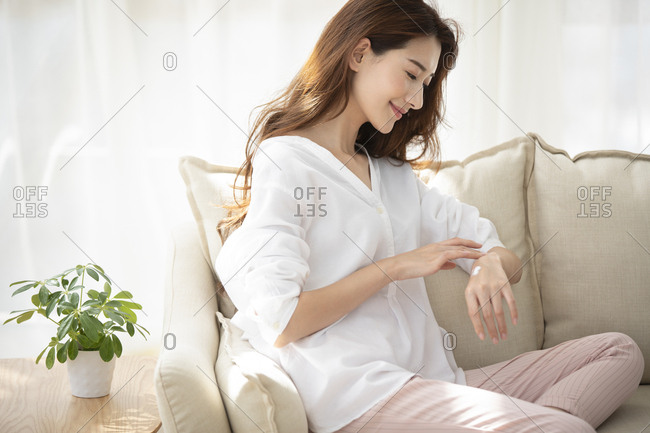 Young Chinese woman applying moisturizer at home