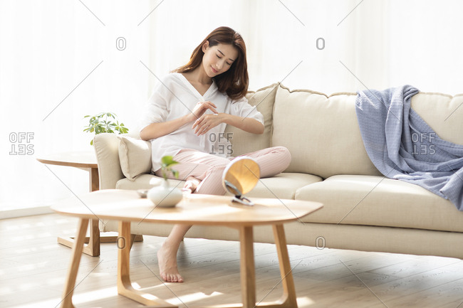 Young Chinese woman applying moisturizer at home
