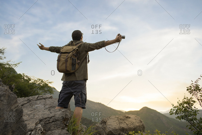 Young Chinese man standing on mountain peak