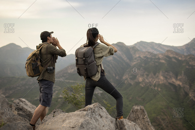 Young Chinese couple shouting on mountain peak