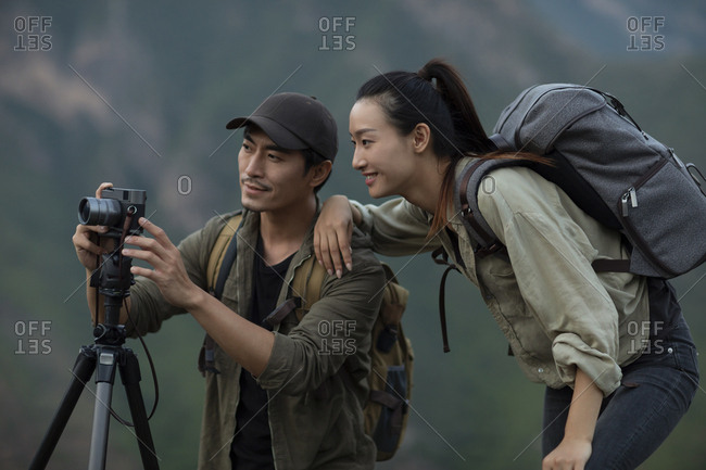 Young Chinese couple taking photos with camera outdoors