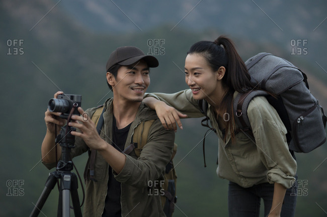 Young Chinese couple taking photos with camera outdoors