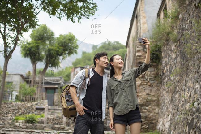 Young Chinese couple taking selfie with smartphone in village
