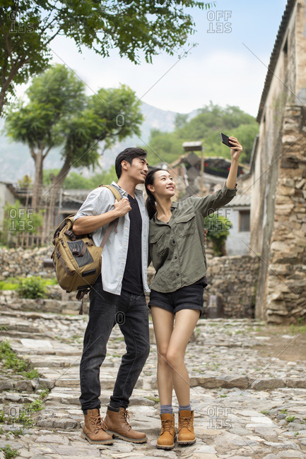 Young Chinese couple taking selfie with smartphone in village