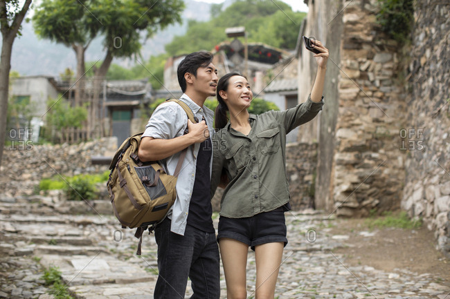 Young Chinese couple taking selfie with smartphone in village