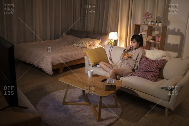 Young Chinese woman watching TV on sofa