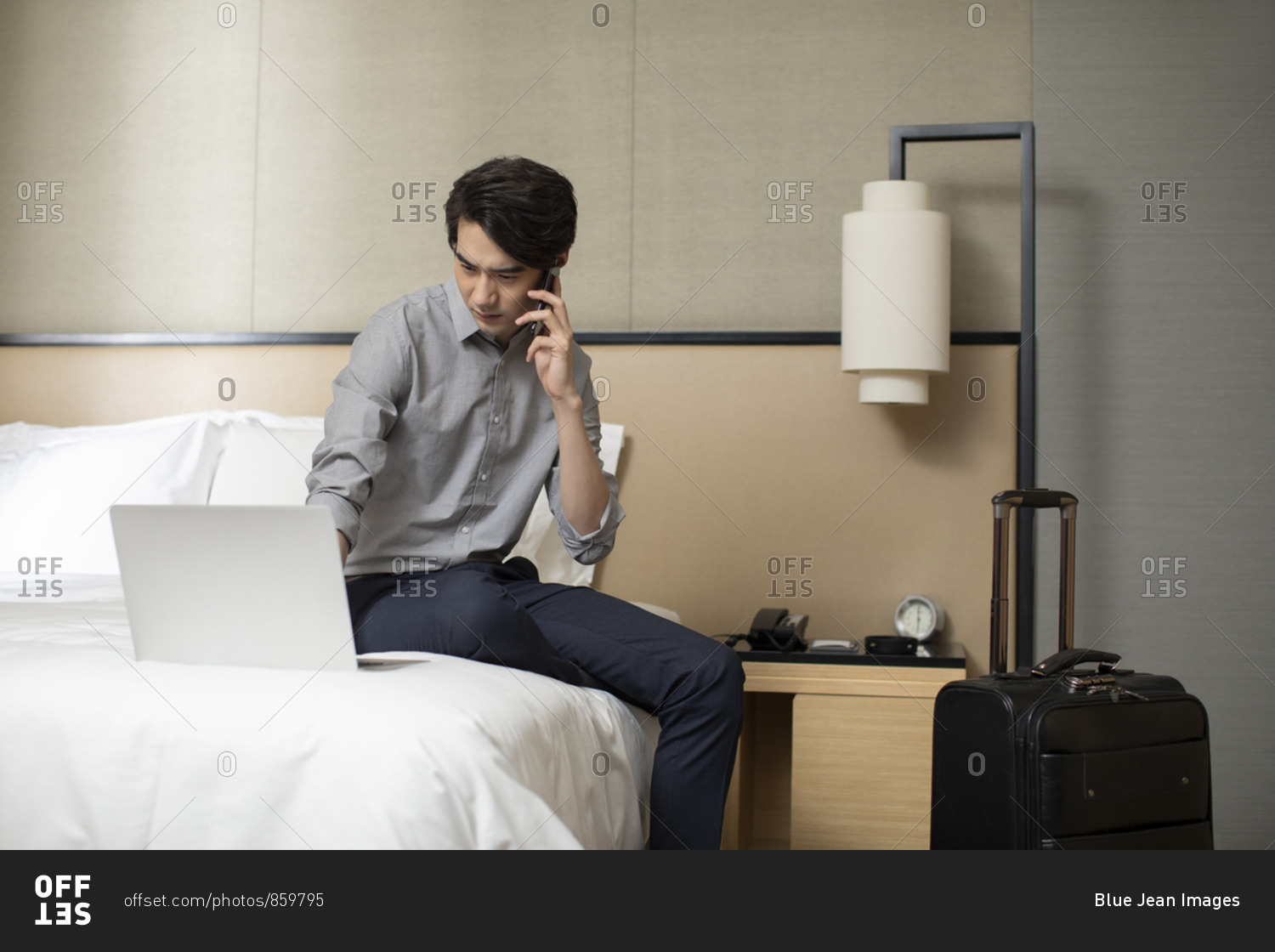 Young Chinese businessman using smartphone in hotel room
