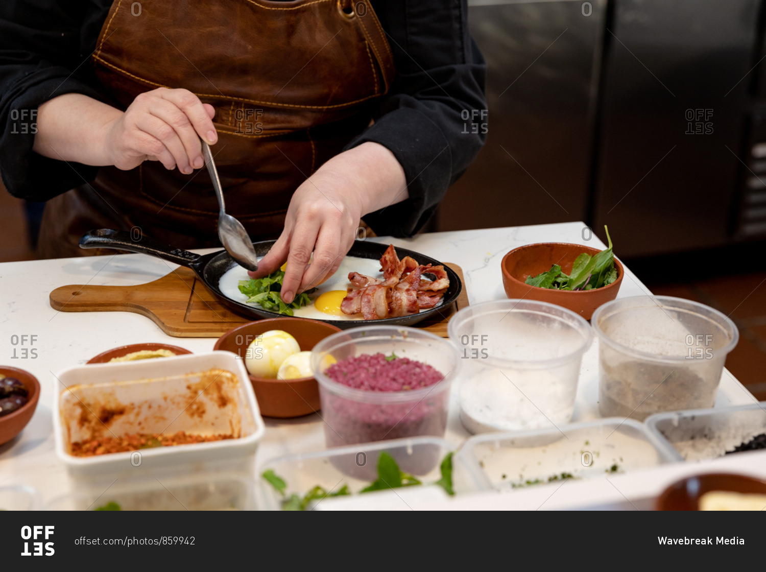 Front view mid section of a Caucasian female chef arranging food to be served in a pan in a restaurant kitchen