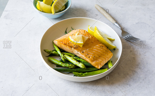 Plate of grilled salmon, asparagus, and green beans with lemon wedges