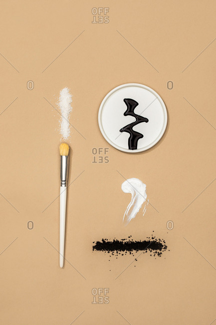Minimalistic composition of natural cosmetic creams and scrubs and a brush on pastel background.