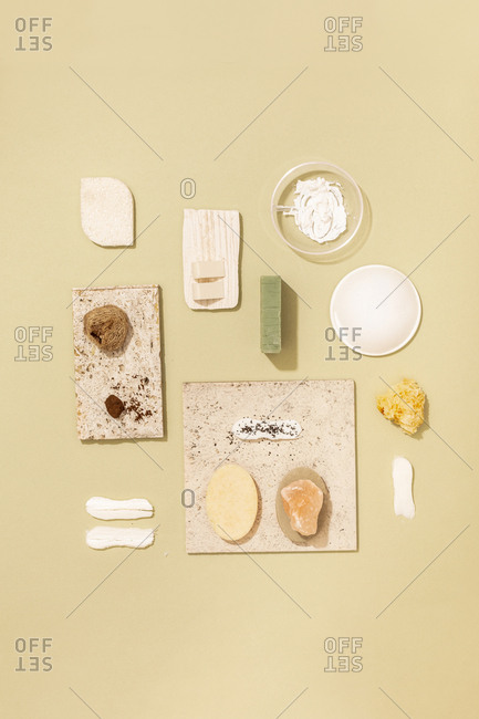 Minimalistic composition of natural soaps and cosmetic creams and scrubs on pastel background.