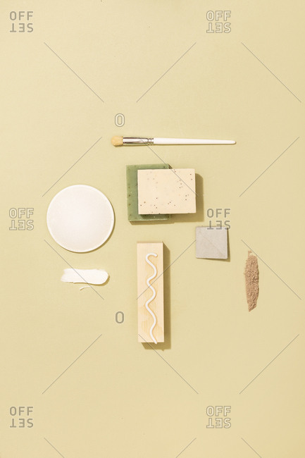 Minimalistic composition of natural soaps and cosmetic creams and scrubs on pastel background.
