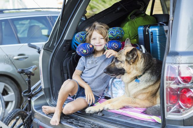 5 year old boy with his German Shepherd dog, in back of  SUV