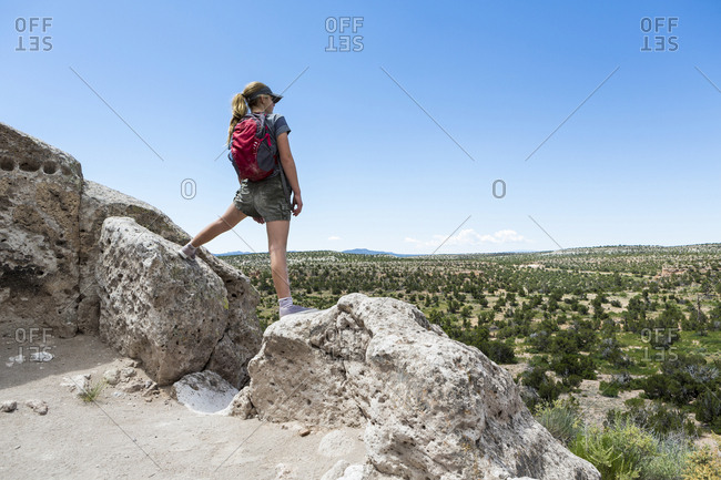 Rear view of  teenage girl hiker overlooking desert vista at the Tsankawi Ruins