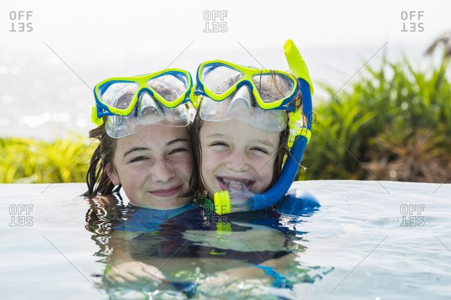 A teenage girl and her 5 year old brother in pool, smiling