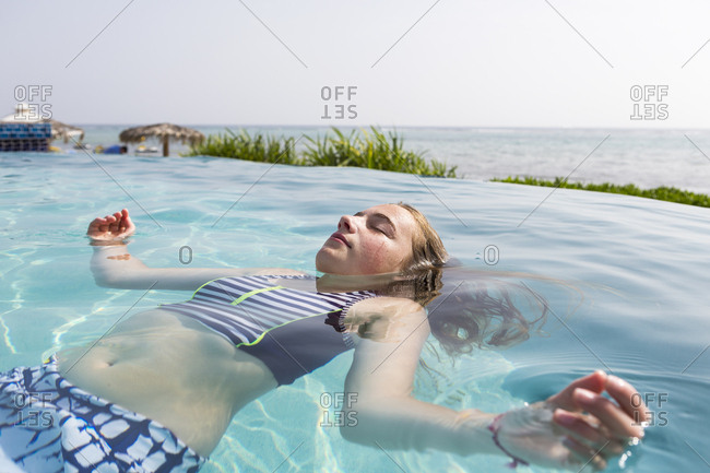A teenage girl floating in infinity pool