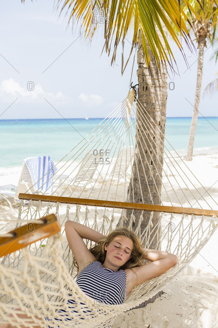 A teenage girl relaxing in a hammock on the beach