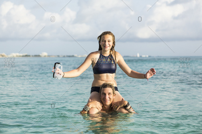 Adult woman standing in ocean water at sunset with her children