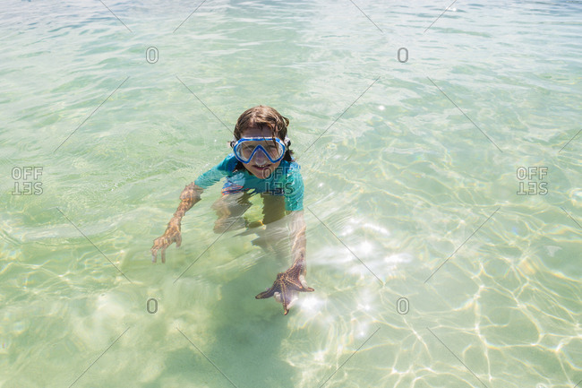 5 year old boy in the water holding a star fish