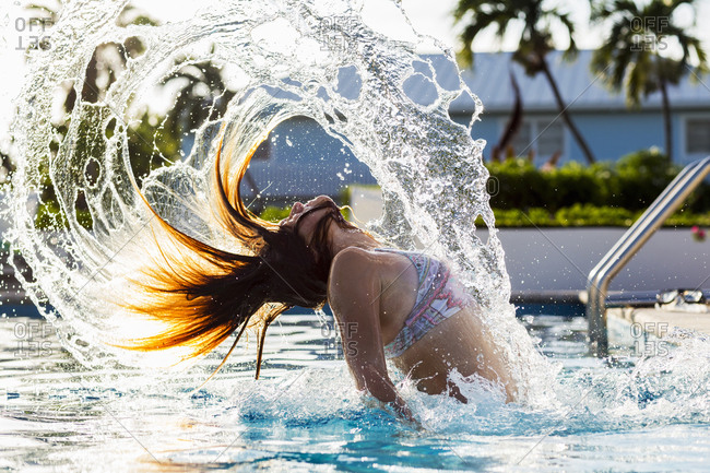A teenage girl tossing her wet hair back, in pool