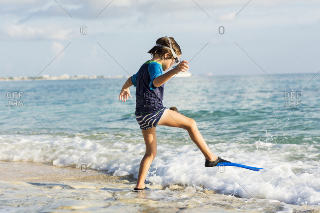 5 year old boy putting his swim fins on at the beach