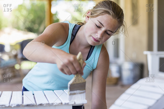 A teenage girl painting  furniture white